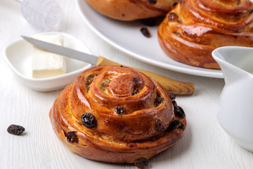 Tasty buns with raisins and butter on a white wooden table. fresh bakery. breakfast. bread. close-up