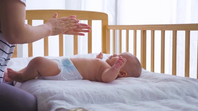 Slow motion of Asian mother massage her baby girl at home lovely 3 months old Chinese baby girl learning to speak facing her mother