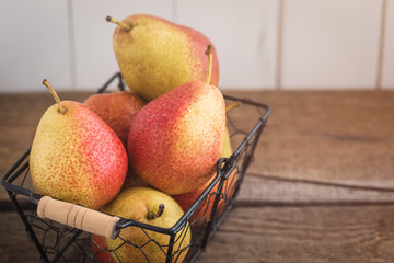 Fresh pears in the basket on the wooden background