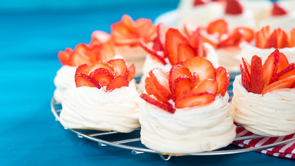 Beautiful pavlova cakes with strawberries on a blue background. Selective focus. Tasty sweet breackfast. Wedding morning. Meringue with cream.