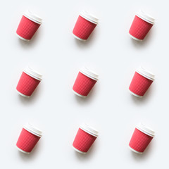 Many red coffee takeaway paper cups as seamless pattern on white background. Flat lay style. Top view.