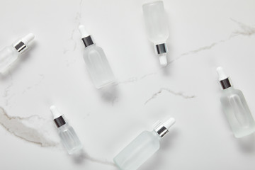 top view of cosmetic glass bottles on white surface