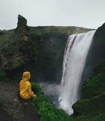 Beautiful waterfall in Iceland. Couple in raincoats looking on scenic high waterfall.