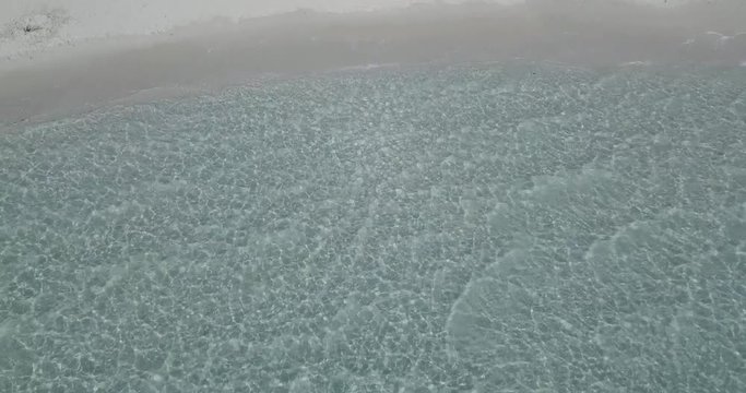AERIAL 4K Clear water with small ripples on a sunny day on a sandy mediterranean beach