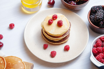 Close up view on homemade classic american pancakes with fresh berry and honey, morning light on white background. Food for breakfast. Copy space for design. honey, sweet cherry, blackberry, raspberry