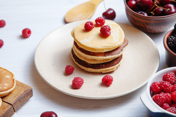Close up view on homemade classic american pancakes with fresh berry and honey, morning light on white background. Food for breakfast. Copy space for design. honey, sweet cherry, blackberry, raspberry