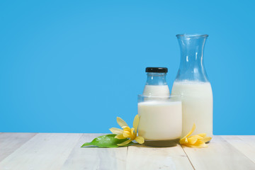 A bottle of rustic milk and glass of milk on a wooden table on a blue background