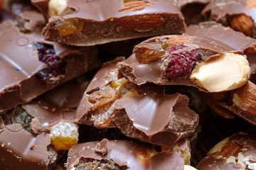 Close up of milk chocolate with hazelnuts and raisins. Milk chocolate in pieces.