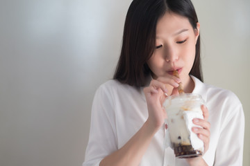 Asian woman drinking iced bubble milk tea; aka boba tea, pearl milk tea, tapioca tea, asian exotic...