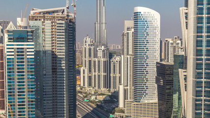 Aerial view of towers in Business Bay with traffic on the road timelapse.