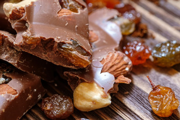 Close up of milk chocolate with hazelnuts and raisins. Milk chocolate in pieces.