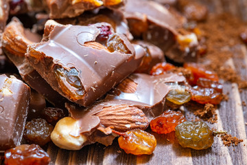 Close up of milk chocolate with hazelnuts and raisins. Milk chocolate in pieces.