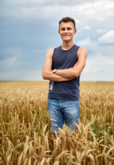 Naklejka na ściany i meble Young farmer in wheat field