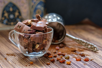 Сhocolate pieces with nuts and raisins on wooden table. Selective focus, wood texture.