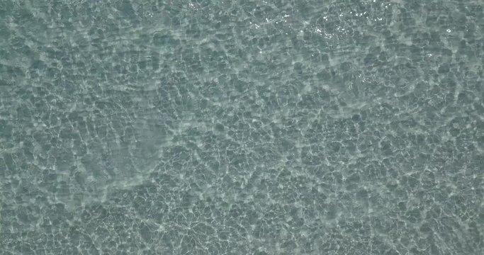 AERIAL 4K Mediterranean white sand beach with clean water on a sunny afternoon