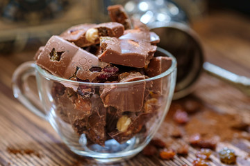 Сhocolate pieces with nuts and raisins on wooden table. Selective focus, wood texture.
