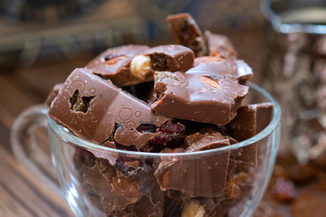 Сhocolate pieces with nuts and raisins on wooden table. Selective focus, wood texture.