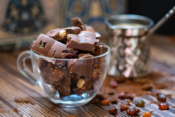Сhocolate pieces with nuts and raisins on wooden table. Selective focus, wood texture.
