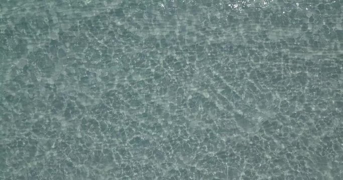 AERIAL 4K Top-down shot pure blue clear sea water with light reflections