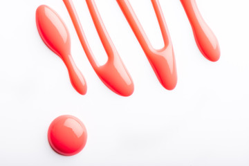 Red nail polish drops on white background.