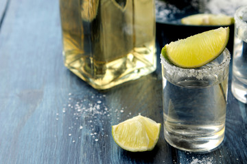 Silver tequila in a glass with salt and lime on a blue wooden table. alcoholic beverages.