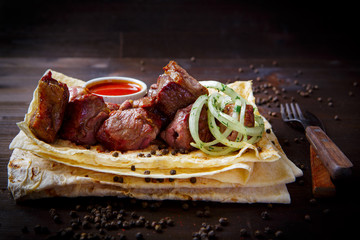 Grill dishes for the restaurant menu. Wooden background. Grilled lamb or pork and onion, pita and sauce.
