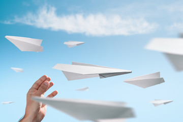 Male hand launching a origami paper plane