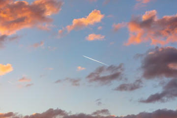 Trail from the plane in the sky at sunset