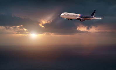 Fototapeta na wymiar the plane of rainbow color flies in the stormy sky with the evening light of the sun. the plane flies over the dark sea