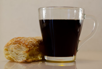 Puff bun with a transparent cup of coffee for Instagram close-ups on the mirror surface. Baking for breakfast. Fragrant Muffin