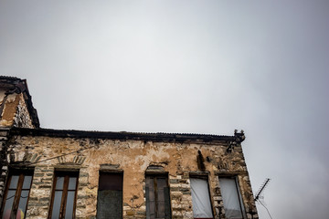 Fototapeta na wymiar Old Greek industrial building under construction with bricks visible, Ioannina downtown, Greece. Moody foggy spring morning, no people, rusty TV antenna silhouette