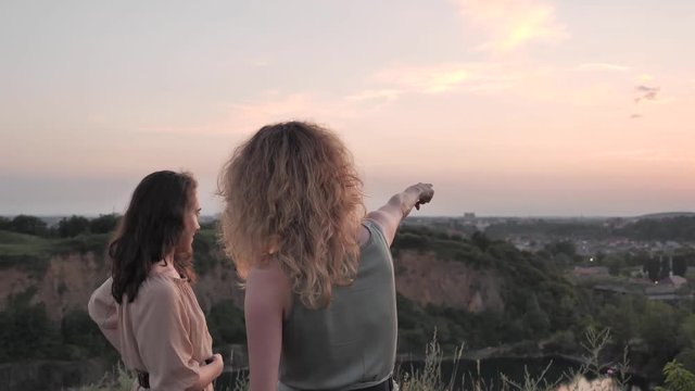 Girls take a selfie against the sunset from the hill overlooking the city. View from the hill to the city. Two girls sharing a photo together.