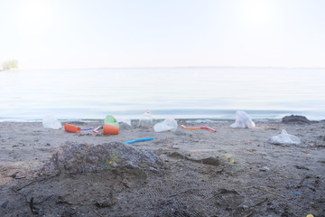 Garbage collection on the beach. Plastic and packages scattered on the beach. A man collects plastic. Ecology protection concept