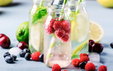 Summer drinks set. Berry, fruit and citrus non-alcoholic refreshing ice cold beverages and cocktails in glass bottles on blue background