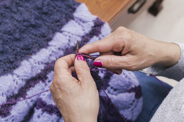 Close-up of a female hands knitting the purple wool