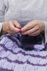 Female hands knitting purple wool