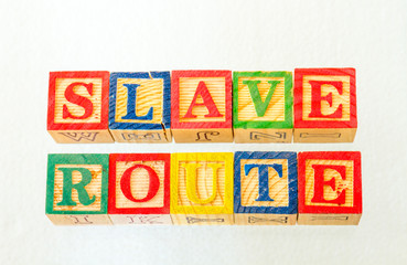 The term slave route visually displayed on a clear background using colorful wooden toy blocks...