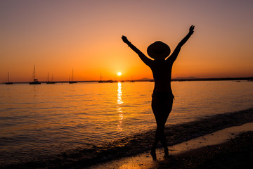 Fototapeta na wymiar Sunset, sexy woman silhouette. Carefree woman enjoying the sunset on the beach. Happy lifestyle. Mallorca. Es Prenc beach.