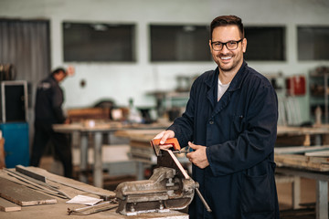 Portrait of a happy worker at metal industry workshop, smiling at camera.