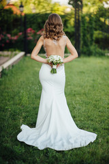 The bride socks her back to the frame and holds a bouquet of colorful flowers.