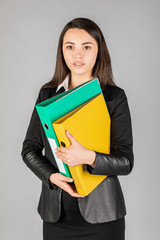 Girl holding a folder of papers on a gray background. business, technology and people concept.