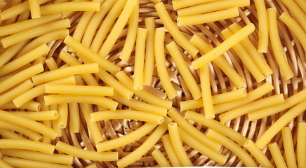 Macaroni, raw pasta in wooden food basket, top view