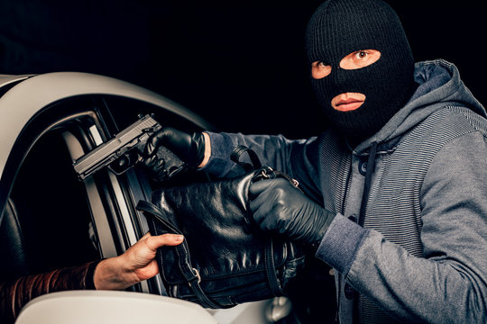 A Masked Robber With A Gun Threatens A Woman In A Car. Robbery.