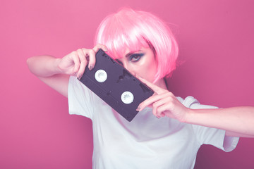 Young girl 90s and VHS cassette on pink background.