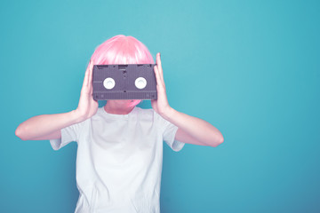 Young girl 90s and VHS cassette on blue background.