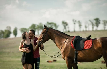 Foto op Canvas Young couple is hugging and kissing next to a horse. © Stanislav