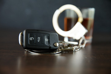 The concept of a DUI. Law hammer, alcohol and car keys on wooden table, dark background