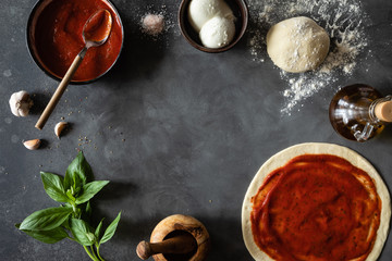 Top view of raw dough, ingredients and spices for pizza Margherita with tomato sauce and Mozzarella...