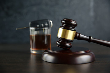 The concept of a DUI. Law hammer, alcohol and car keys on wooden table, dark background