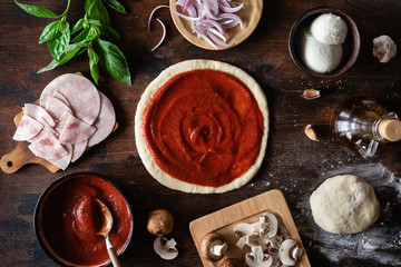 Ingredients for traditional Italian pizza on a dark wooden background. Top view. Pizza recipe and menu. View from above. Space for text. Flat lay